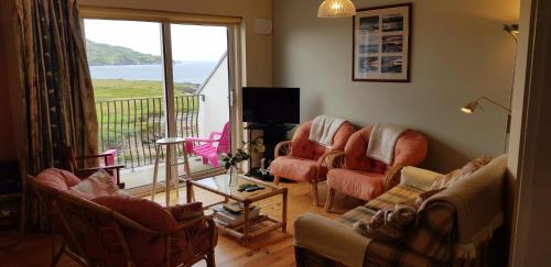 a living room with couches and chairs and a balcony at Beautiful 3 Bed Apartment with Balcony Sea View in Dunfanaghy