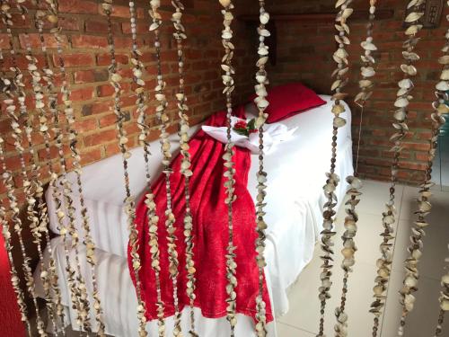 a bed with a red blanket and beads on it at Pousada Alto Astral in Olinda