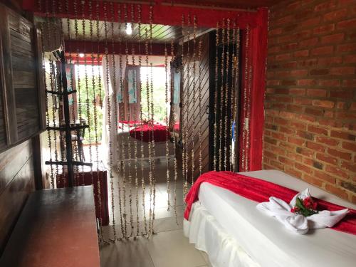 a bedroom with a bed with red curtains and a brick wall at Pousada Alto Astral in Olinda