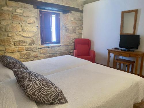 1 dormitorio con 2 camas y silla roja en Peñasalve en Villamoñico