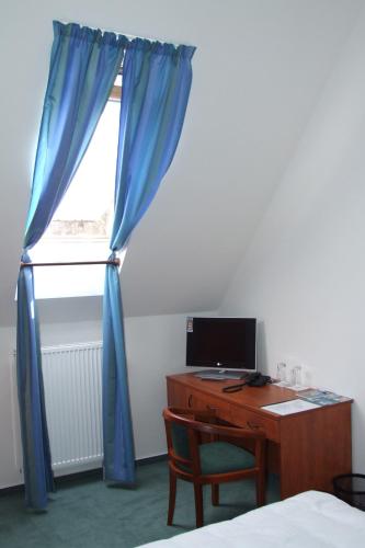 a bedroom with a desk and a window with a blue curtain at Depandance - vedlejší budova u Zámku Třešť in Třešť