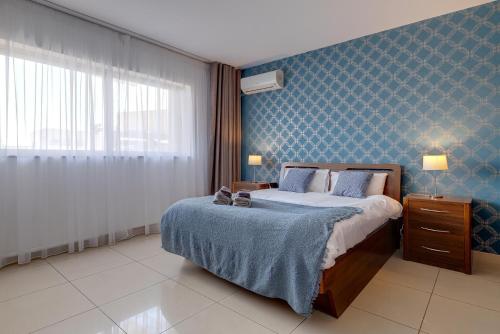 ein Schlafzimmer mit einem Bett und einer blauen Wand in der Unterkunft Luxury Apartment with Balcony, Central Area in Gżira