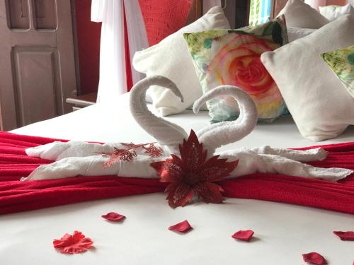 two swans made out of towels on a bed with roses at Pousada Alto Astral in Olinda
