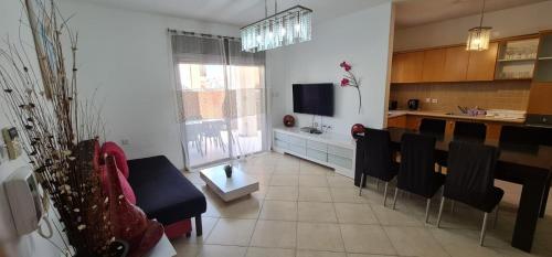 a living room with black chairs and a kitchen at Amdar Holiday Apartments in Eilat