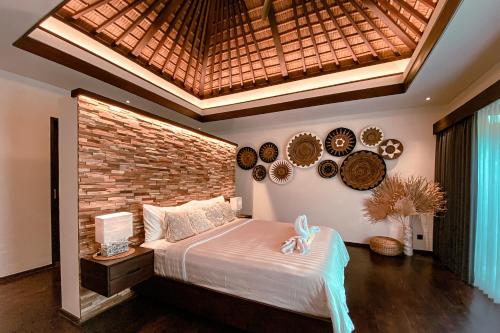 a bedroom with a large bed with a brick wall at Sunset Palms Beach Villa in Jimbaran