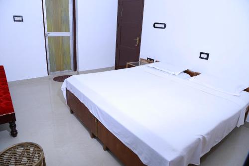 a bedroom with a large white bed and a chair at Lovedale Lakeside Homestay in Alleppey