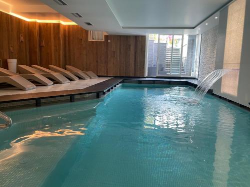 a swimming pool with chairs and a water fountain at ROSENSUITE La Residenza del rosengarten in Pinzolo