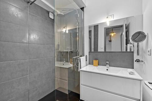 une salle de bain blanche avec un lavabo et un miroir dans l'établissement LE REGANS - Charmant appartement en tomette, à Toulouse
