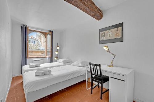 une chambre avec deux lits et un bureau et une fenêtre dans l'établissement LE REGANS - Charmant appartement en tomette, à Toulouse