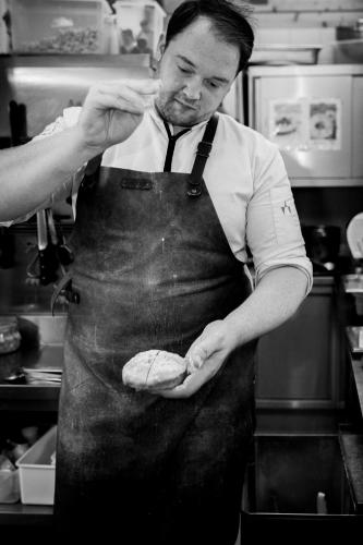 a man in a kitchen holding a piece of food at Adults Only Boutique-Hotel Unterlechner in Sankt Jakob in Haus