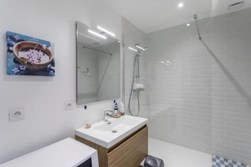 La salle de bains blanche est pourvue d'un lavabo et d'une douche. dans l'établissement L'ILE AUX MOUETTES - en plein Intra-Muros, à Saint-Malo