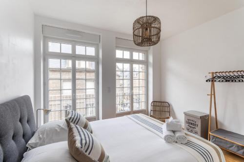 a bedroom with a bed and two windows at L'ILE AUX MOUETTES - en plein Intra-Muros in Saint Malo