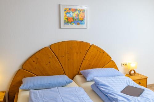 a bedroom with a wooden headboard and two blue pillows at Gasthaus Rössle in Bretzfeld