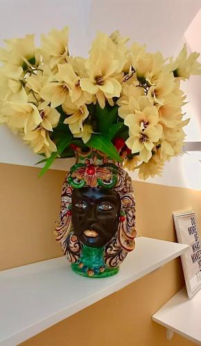 a vase filled with yellow flowers sitting on a shelf at Relais Roma Vaticano - METRO station Ottaviano in Rome