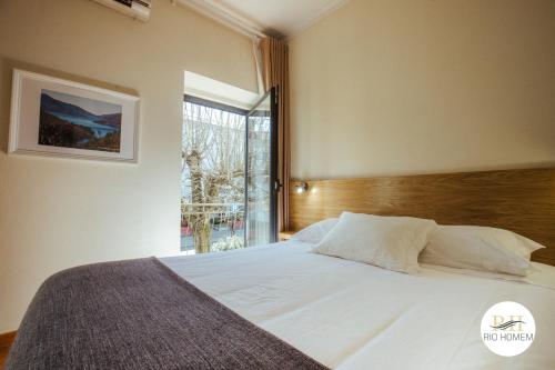 a bedroom with a white bed with a window at Rio Homem in Terras de Bouro