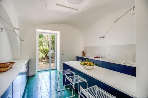 een keuken met blauwe en witte werkbladen en stoelen bij Villa La Luce 5 Bedrooms in the Town Center in Massa Lubrense