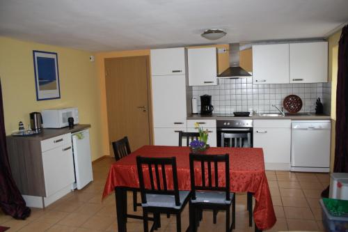 eine Küche mit einem Tisch und Stühlen sowie eine Küche mit weißen Schränken in der Unterkunft Ferienwohnung Peerenboomshof in Kranenburg