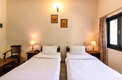 a room with two beds and a table and a window at Gulaab Niwaas Palace in Pushkar
