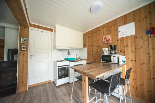 a kitchen with wooden walls and a wooden table and chairs at Lesjaskogsvatnet Camping in Lesjaskog