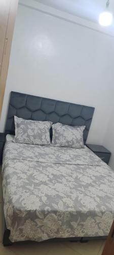 Schlafzimmer mit einem Bett mit blauem Kopfteil und Kissen in der Unterkunft Appartement a louer pour les vacances in Tangier