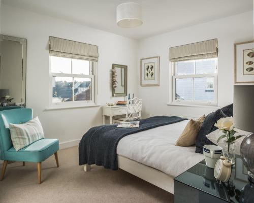 a bedroom with a bed and a blue chair at Camber Beach House in Camber