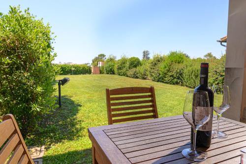 a bottle of wine sitting on a wooden table with two glasses at Residenza Principina in Principina Terra