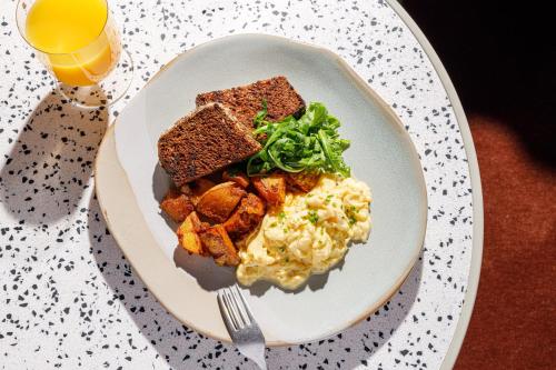 a plate of food with toast and vegetables and a glass of orange juice at TRIBE London Canary Wharf in London