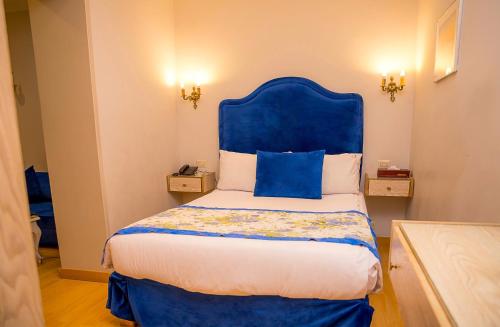 a bed with a blue headboard in a room at San Giovanni Stanly Hotel in Alexandria