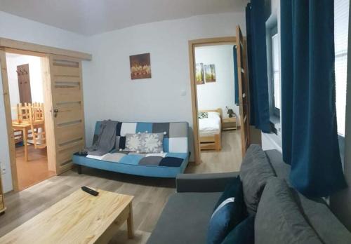 a living room with a blue couch and a table at Apartmán Na zjazdovke, chata Borovica, Valča in Valča