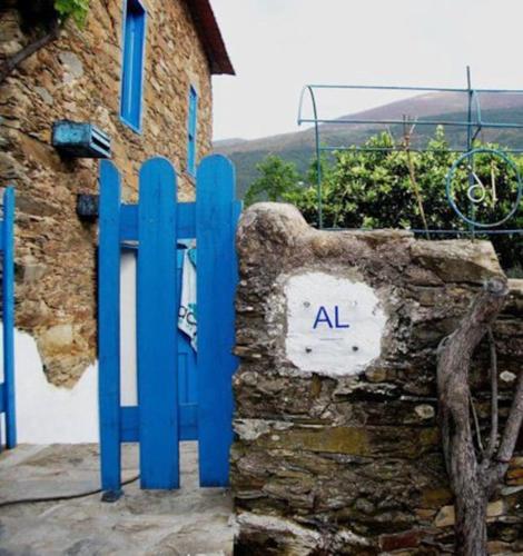 a blue gate in front of a stone building at Refúgio da Estrela in Aguincho