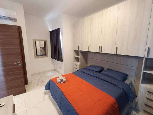 a bedroom with a bed with an orange and blue blanket at Blu-M Central in Qormi