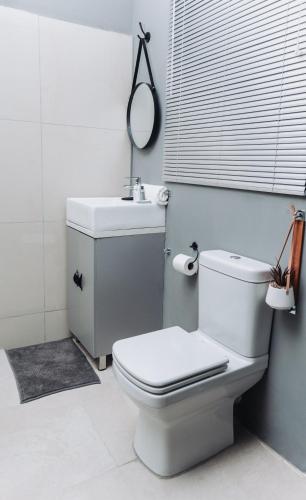 a white bathroom with a toilet and a sink at Mash-G Villa Guest House in Phalaborwa