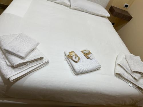 Una cama blanca con dos toallas y dos anillos. en B&B Il Cuore del Borgo, en Papasidero