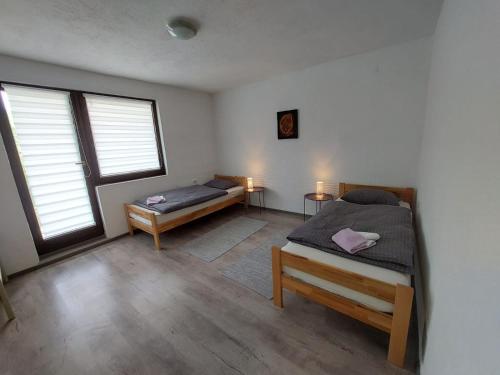 a bedroom with two beds and two windows at Apartman Emanuel in Jajce