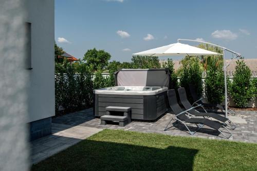 a backyard with a hot tub and two chairs and an umbrella at Style Inn Apartmanok in Veszprém