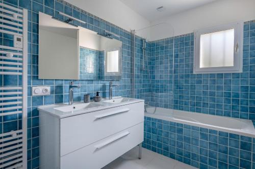 une salle de bain carrelée bleue avec un lavabo et une baignoire dans l'établissement Maison pour 8 personnes à 300 m de la plage, à Pornic