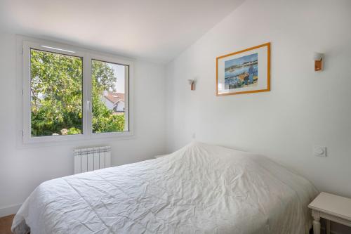 une chambre blanche avec un lit et une fenêtre dans l'établissement Maison pour 8 personnes à 300 m de la plage, à Pornic