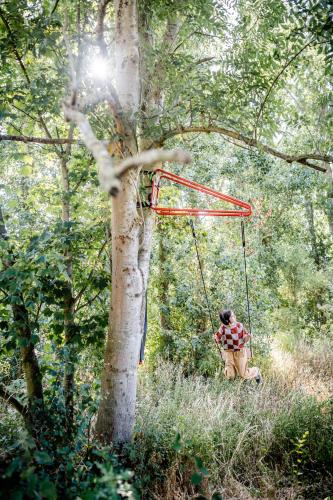 a person sitting on a swing in a tree at les Cabanes d'Ostende in Ostend