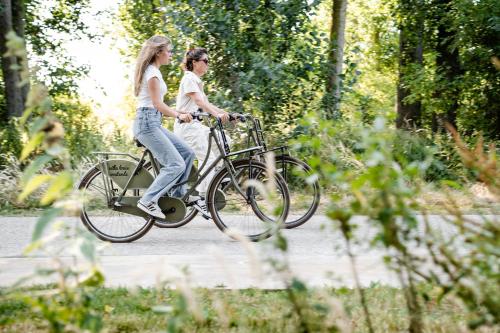 two women riding a bike down a path at les Cabanes d'Ostende in Ostend