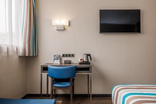 a room with a desk with a blue chair and a tv at Hotel Ronda Lesseps in Barcelona