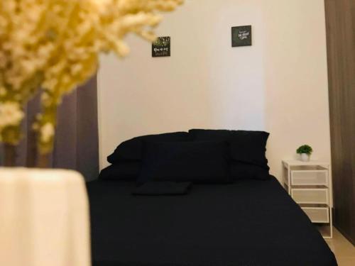 a bedroom with a bed with black sheets and pillows at Cozy Bedroom FAME Condo Greenfield EDSA MRT Shaw in Manila
