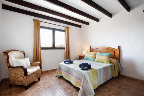 um quarto com uma cama, uma cadeira e uma janela em Casa Cucu em Lajares