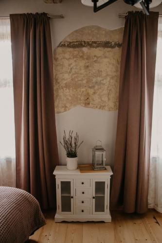 a bedroom with curtains and a table with a clock on it at Zelta Apelsīna apartamenti in Kuldīga