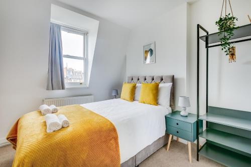 a bedroom with a large white bed with yellow pillows at Modern 2 Bed Apartment in Central London, Kensington in London