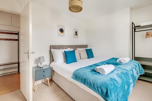 a bedroom with a large bed with blue and white pillows at Modern 2 Bed Apartment in Central London, Kensington in London