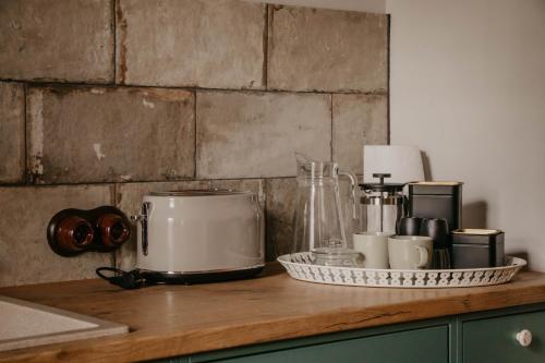 a counter top with a coffee maker and cups at Zelta Apelsīna apartamenti in Kuldīga