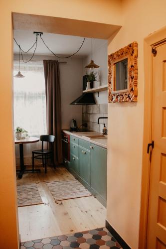 a kitchen with green cabinets and a table with a window at Zelta Apelsīna apartamenti in Kuldīga