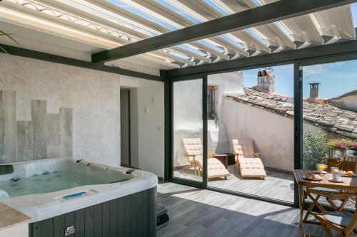 a patio with a tub and a table and chairs at Nuit Etoilée in LʼIsle-sur-la-Sorgue