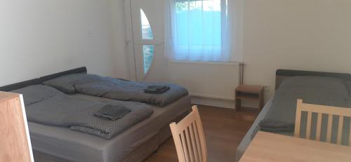 a bedroom with two beds and a table and a window at Borti Apartman in Zamárdi