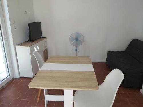 einen Tisch und Stühle im Wohnzimmer mit Ventilator in der Unterkunft Maisonnette 40 m2 pour 5 personnes in Paray-le-Monial